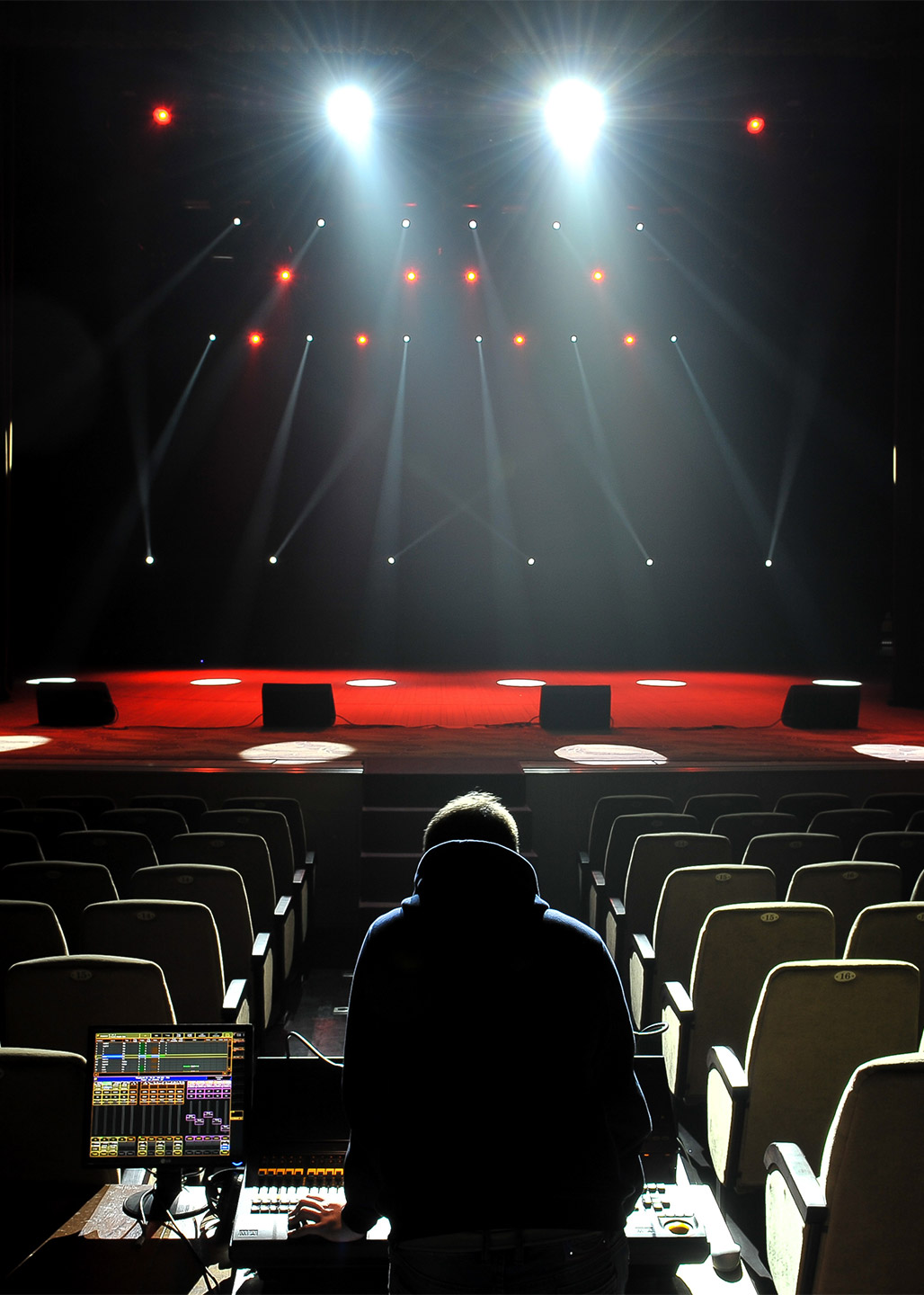 A man rehearsing the lighting for an upcoming show in an empty theatre.