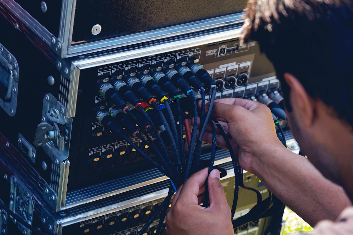 audio stagehand plugging audio cable on studio system boxes.