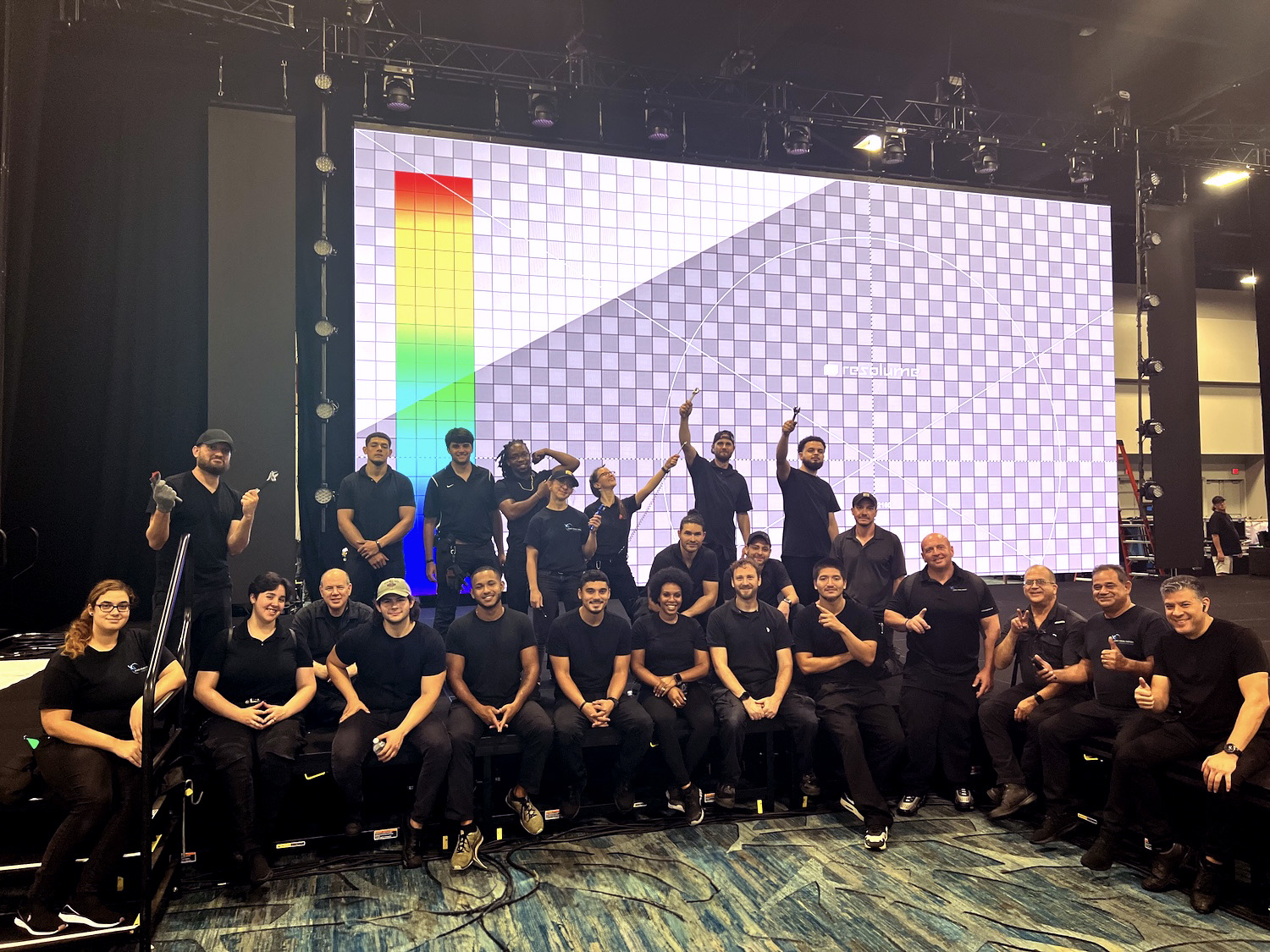 An Audio Visual Nation crew posing in front of a large projector screen at an event