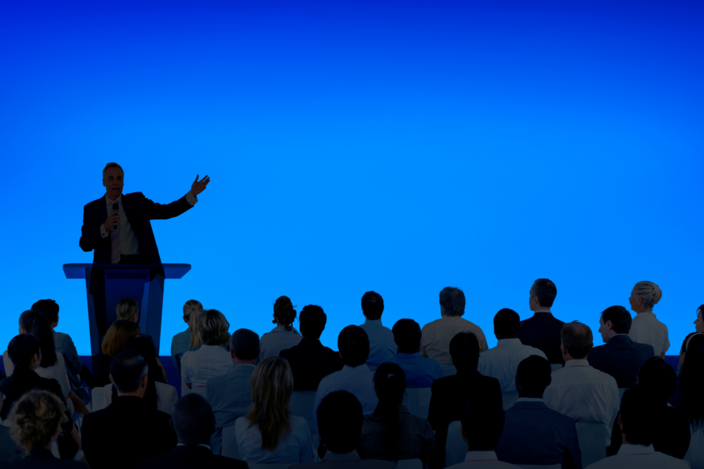 Corporate businessman giving a presentation to a large audience