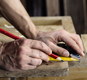 A Man Drawing With a Wooden Ruler on Wood. Computer network technician.